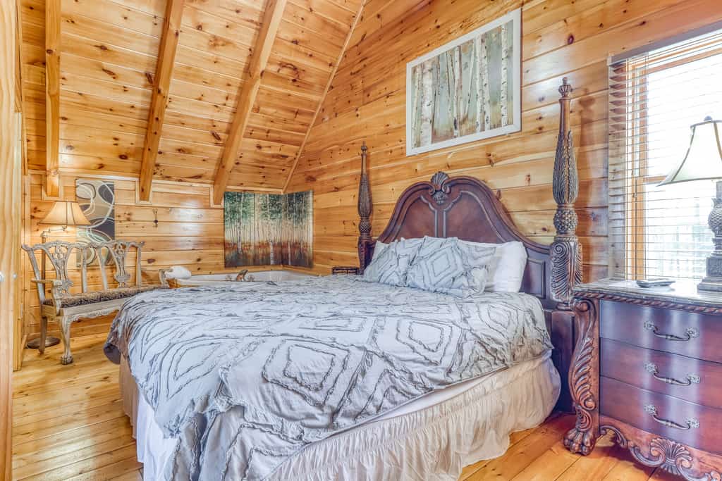 A wide view of a luxurious room with a large bed, wooden furniture, and a vaulted ceiling.