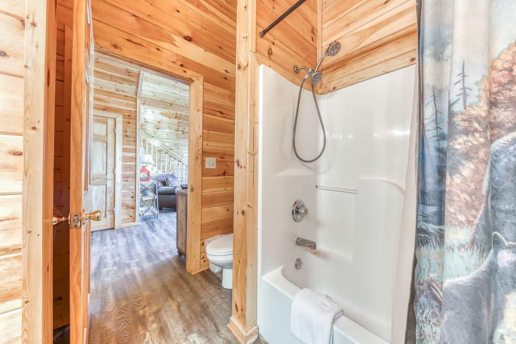 A bathroom with a shower, toilet, and wooden walls