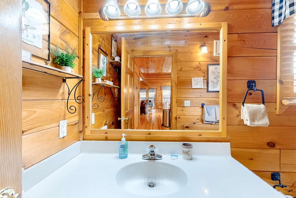 A bathroom sink area with a large mirror, wooden paneling, and a white sink.