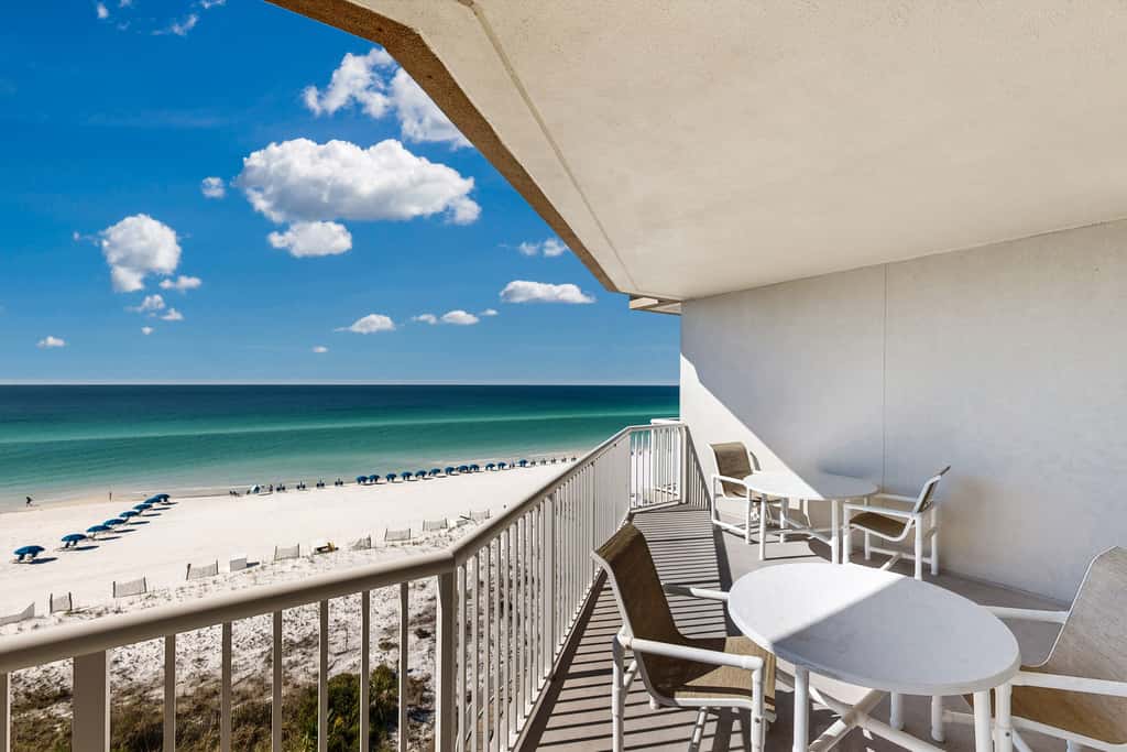 Beachfront condo with beach chairs, an umbrella, and a pool