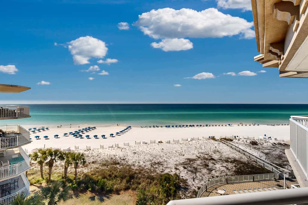 Beachfront condo with beach chairs, an umbrella, and a pool