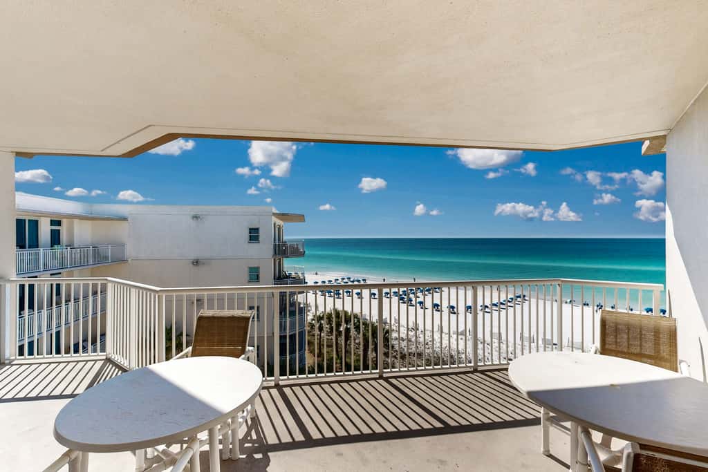 Beachfront condo with beach chairs, an umbrella, and a pool