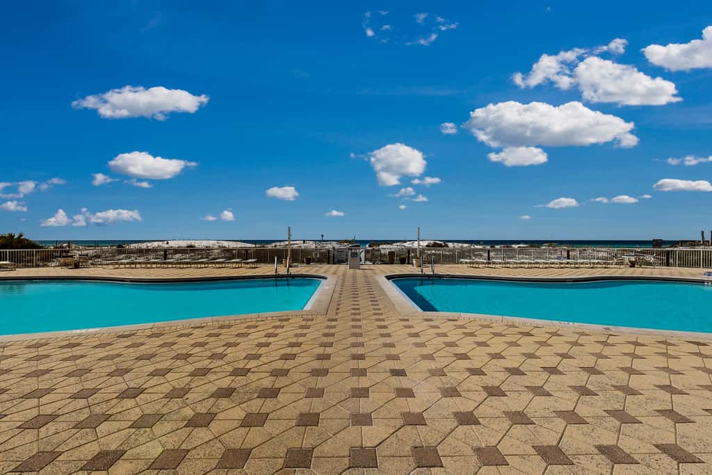 Beachfront condo with beach chairs, an umbrella, and a pool