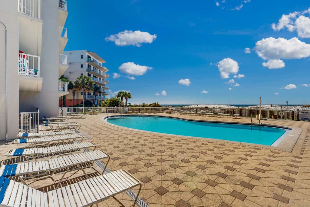Beachfront condo with beach chairs, an umbrella, and a pool