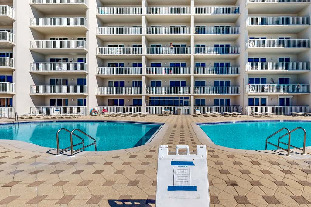 Beachfront condo with beach chairs, an umbrella, and a pool
