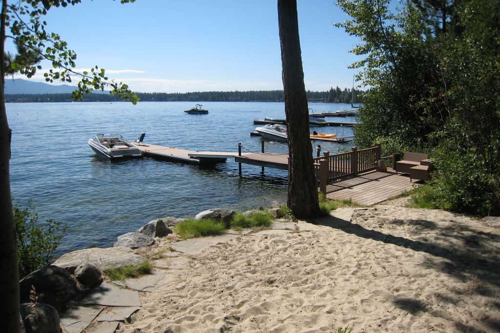 A classic lakefront cabin with floor-to-ceiling views of Payette Lake, private beach access, and a nostalgic McCall feel throughout. This cozy retreat features multiple sleeping spaces upstairs, a covered deck overlooking the lake, and a private dock with seating by the water. Wood-paneled interiors and vintage cabin charm create the quintessential McCall getaway experience.