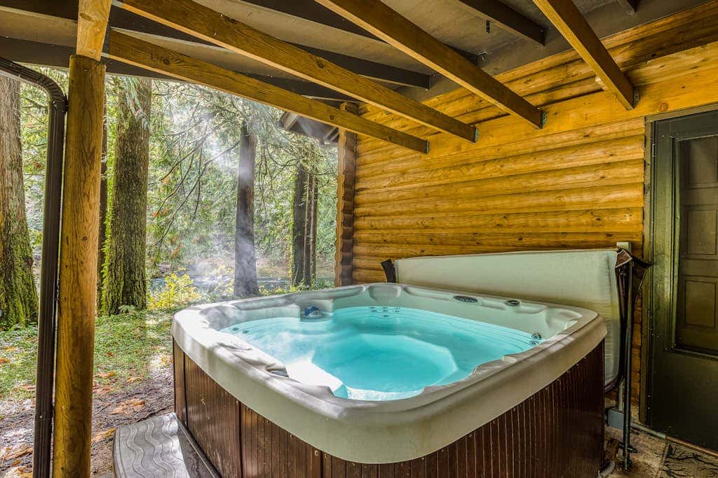 Spacious riverfront lodge with beach access, private hot tub & forest views