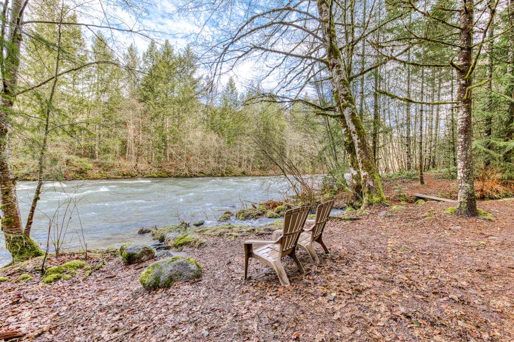 Historic riverfront Steiner cabin in forest with firepit, deck, & patio lounging