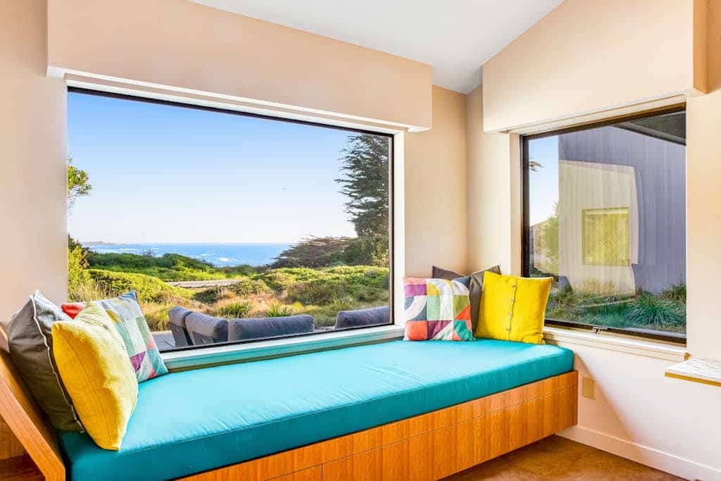 Out where the road ends and the bluff takes over, this home is nearly surrounded by ocean — and every single room has a view of it. The living room is wrapped in floor-to-ceiling sliding glass on two sides, with ocean views out both — waves to the north over Smugglers Cove, waves to the south toward Black Point. Whale spouts from the sofa, waves from your pillow, fog with your coffee. Sleeps 6 in 3 bedrooms, a 7-minute walk to Pebble Beach. The only agenda here is yours.