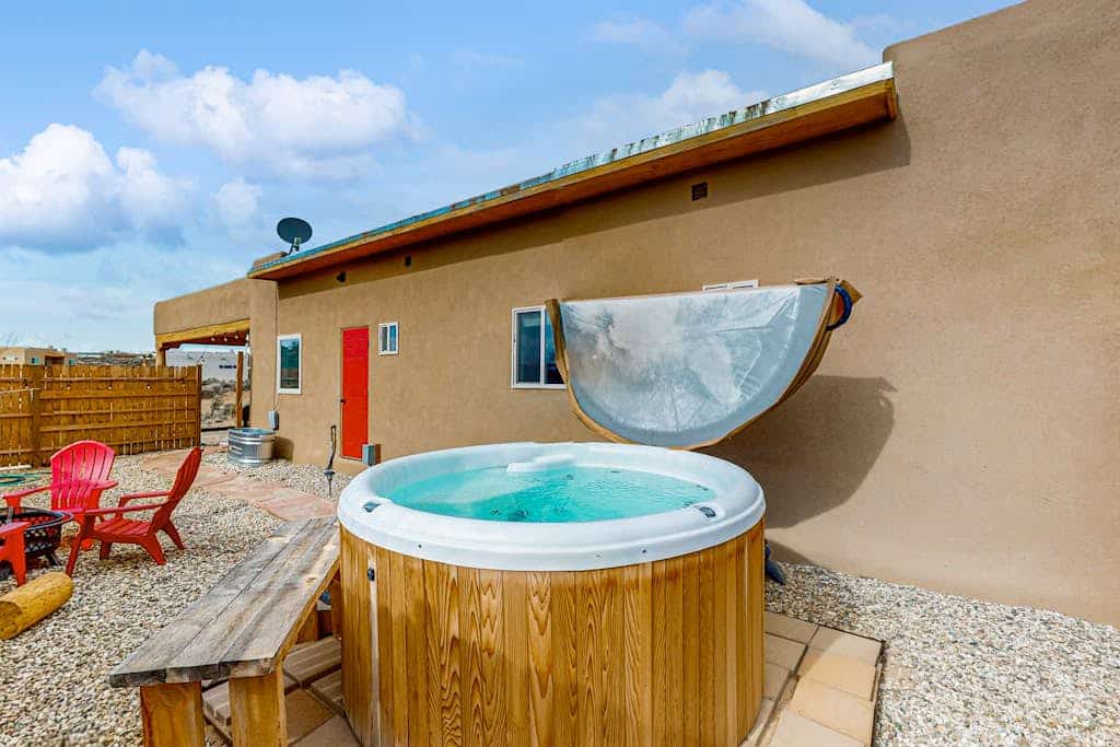 Welcome to Margaritavilla, a fun, music-themed adobe home in El Prado with sweeping mountain and valley views. Soak in the private hot tub and gather at the fire pit in the enclosed yard, then warm up by the wood stove with games, puzzles, and a Bluetooth sound system. Cook in the well-equipped kitchen and relax in the bright living room. Dog-friendly and a short drive from Taos Plaza and the ski valley, it is a laid-back high-desert getaway.