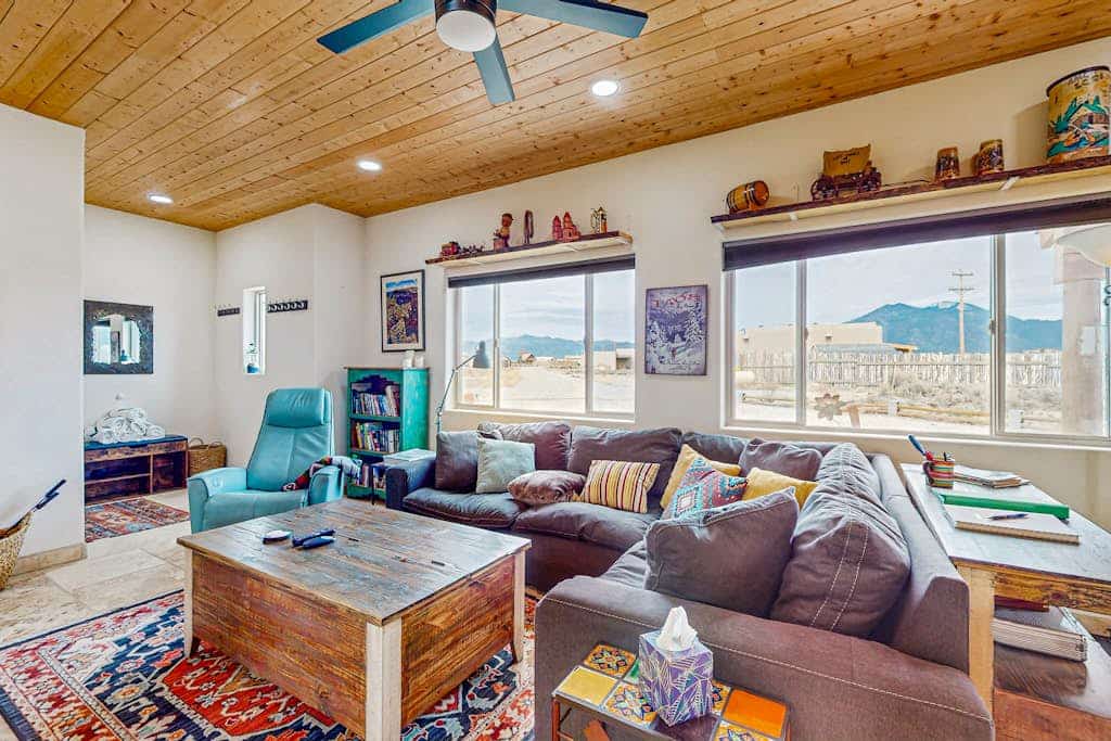 Welcome to Margaritavilla, a fun, music-themed adobe home in El Prado with sweeping mountain and valley views. Soak in the private hot tub and gather at the fire pit in the enclosed yard, then warm up by the wood stove with games, puzzles, and a Bluetooth sound system. Cook in the well-equipped kitchen and relax in the bright living room. Dog-friendly and a short drive from Taos Plaza and the ski valley, it is a laid-back high-desert getaway.