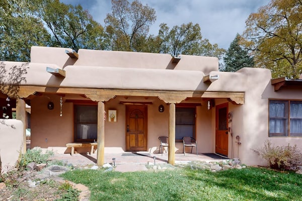 Welcome to Adobe Retreat, a light-filled historic adobe just four blocks from Taos Plaza. Gather under soaring viga ceilings by the wood-burning fireplace, cook in a tile-trimmed kitchen with a sunny breakfast bar, and step out to a private, adobe-walled courtyard framed by green lawns and old cottonwoods. With local art at every turn and radiant-heated floors underfoot, this single-level home is a peaceful base for art, dining, and mountain adventures.