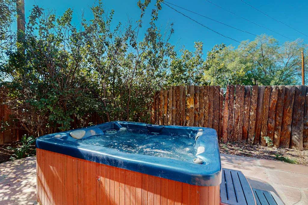 Welcome to Bedside Manor, a character-filled adobe home on a lush .76-acre lot just minutes from Downtown Taos. Soak in the private hot tub under the stars, gather around the kiva fireplace beneath soaring viga-and-skylight ceilings, and grill dinner by the covered outdoor fireplace. With two king bedrooms, a futon study, a spa-like bath, mountain views, and room for the whole family plus a dog, this single-level retreat is a peaceful Taos basecamp.
