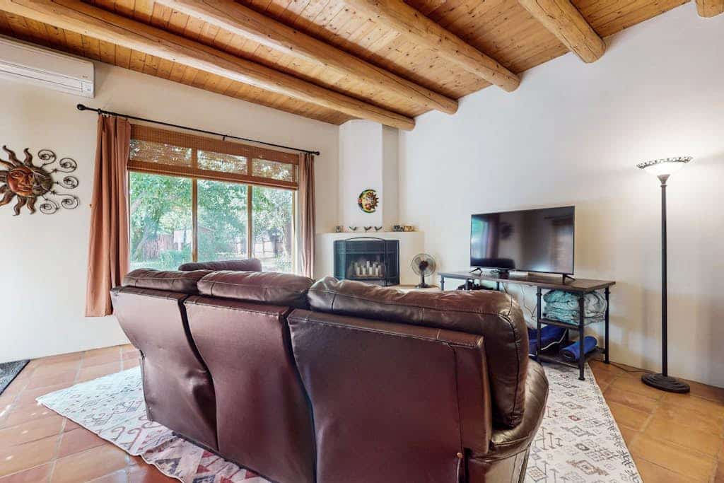 Welcome to Casa Belleza, a sunlit Southwestern adobe tucked on a quiet cul-de-sac near Taos. Gather in the open living space around the kiva-style fireplace, cook in a cheerful turquoise kitchen, and step out to a fully fenced, tree-shaded yard your dog will love. With two queen bedrooms, mini-split AC, and a covered portal for easy evenings, this single-level home is a relaxed, pet-friendly base for galleries, the Plaza, and Taos adventures.
