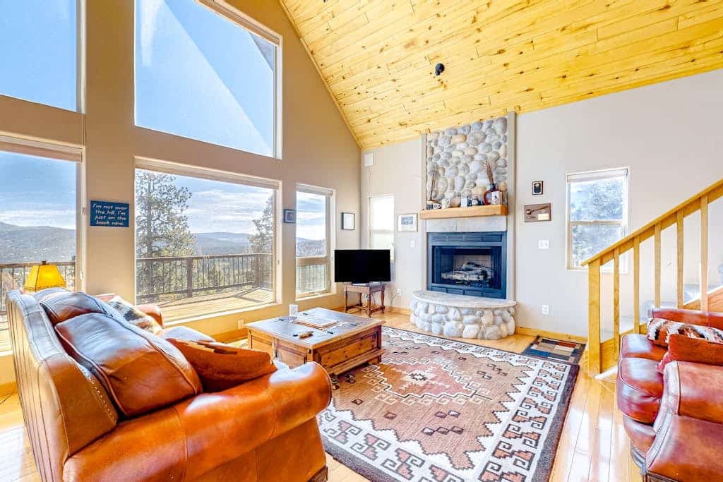 Welcome to Peter's Place, a soaring cabin-style home set among the pines just three miles from Angel Fire Resort. Gather in the vaulted great room around the river-rock gas fireplace, take in panoramic mountain and valley views through walls of windows, and step onto the expansive decks for coffee at sunrise and stars at night. Cook in the granite kitchen, soak in the primary suite's jetted tub, and spread out across three levels with room for ten.