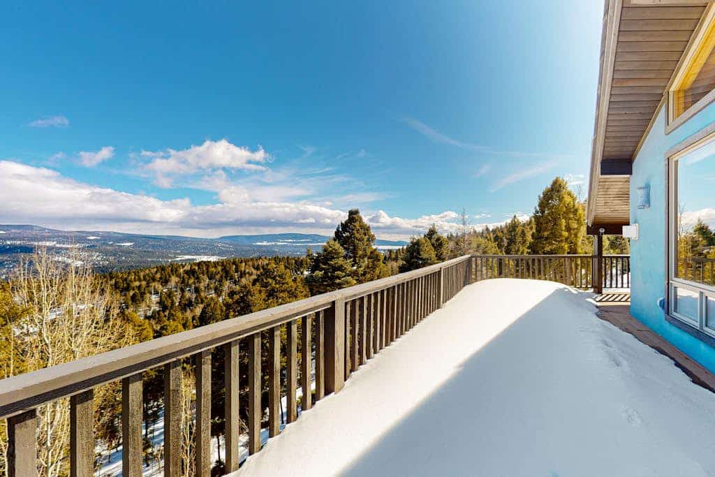 Welcome to Le Chalet Bleu, a striking blue mountain chalet perched high above Angel Fire with panoramic views of the valley, mountains, and distant lake. Sleeping eight across three bedrooms, this spacious 4,700+ sq ft retreat is built for gathering, with a vaulted great room and walls of windows, a full kitchen, an in-home movie theater, and a game room with pool and ping-pong. Soak in the jetted tub, warm up by the gas fireplace, and watch the sky change from the wraparound deck.