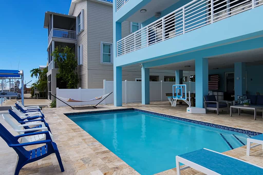 Sprawling waterfront home with pool, outdoor kitchen, game table, grill, & W/D