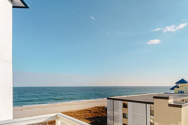 Ocean-view condo with shaded balcony, central AC, W/D, pool, gym & coastal decor