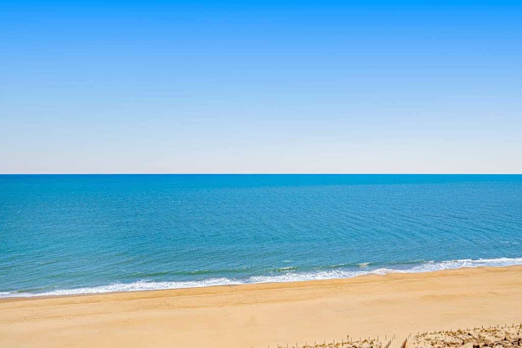 Beachfront condo with wrap-around balcony, modern interior, pools, & gym