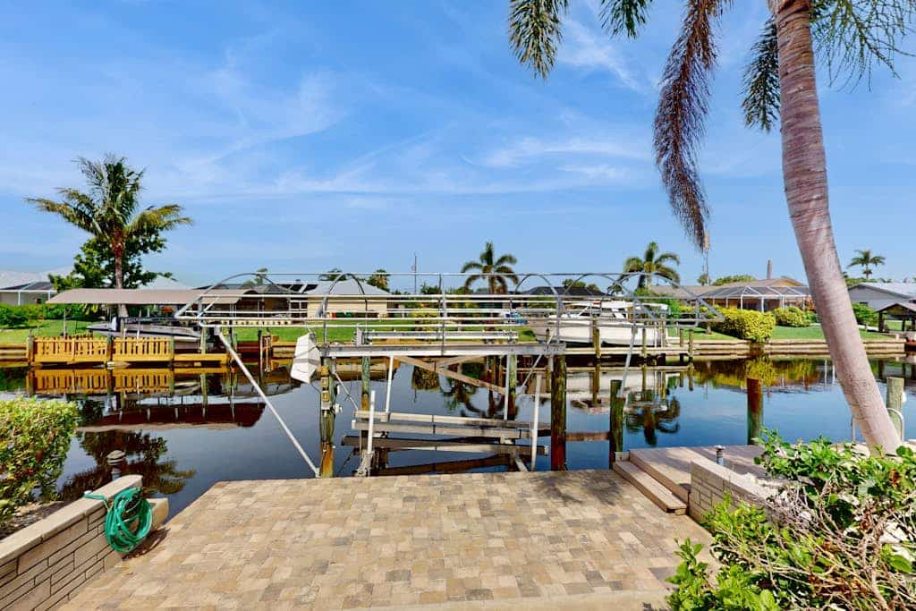 Canal-front home with screened pool, dock access, patio, grill, AC, & W/D