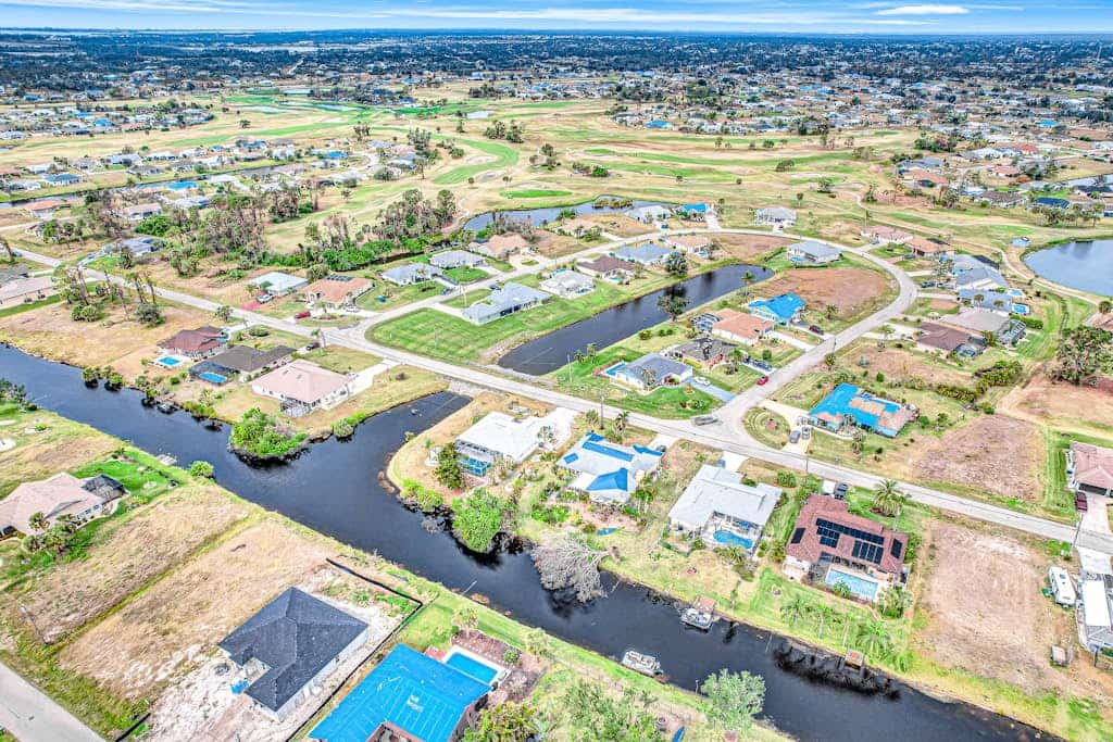 Palm-lined waterfront retreat with enclosed pool, inviting patio, & central AC
