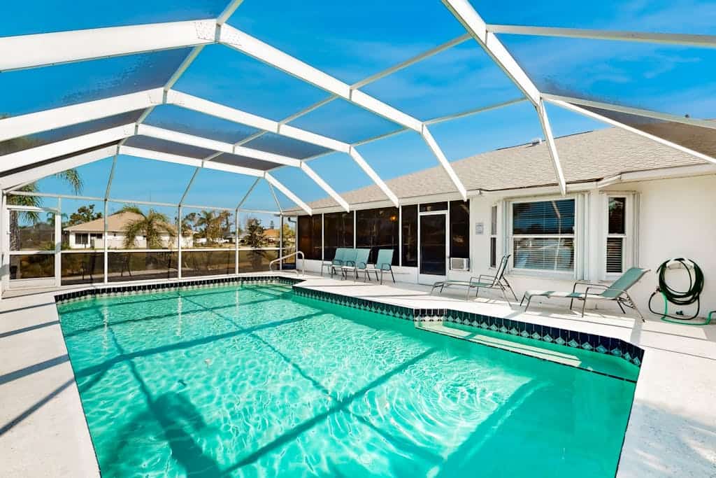 Palm-lined waterfront retreat with enclosed pool, inviting patio, & central AC