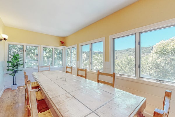 Furnished 30-night-minimum rental on Fitch Mountain, two miles from Healdsburg Plaza. Utilities and Wi-Fi included. Five bedrooms, one and a half baths, own washer and dryer, a desk, air conditioning, and one designated parking spot. A 1940s Camp Rose cottage with a stone fireplace, a separate dining room, a fenced play yard with a swing set, and Russian River valley views from most rooms. Stays of 30 to 90 nights. No pets.