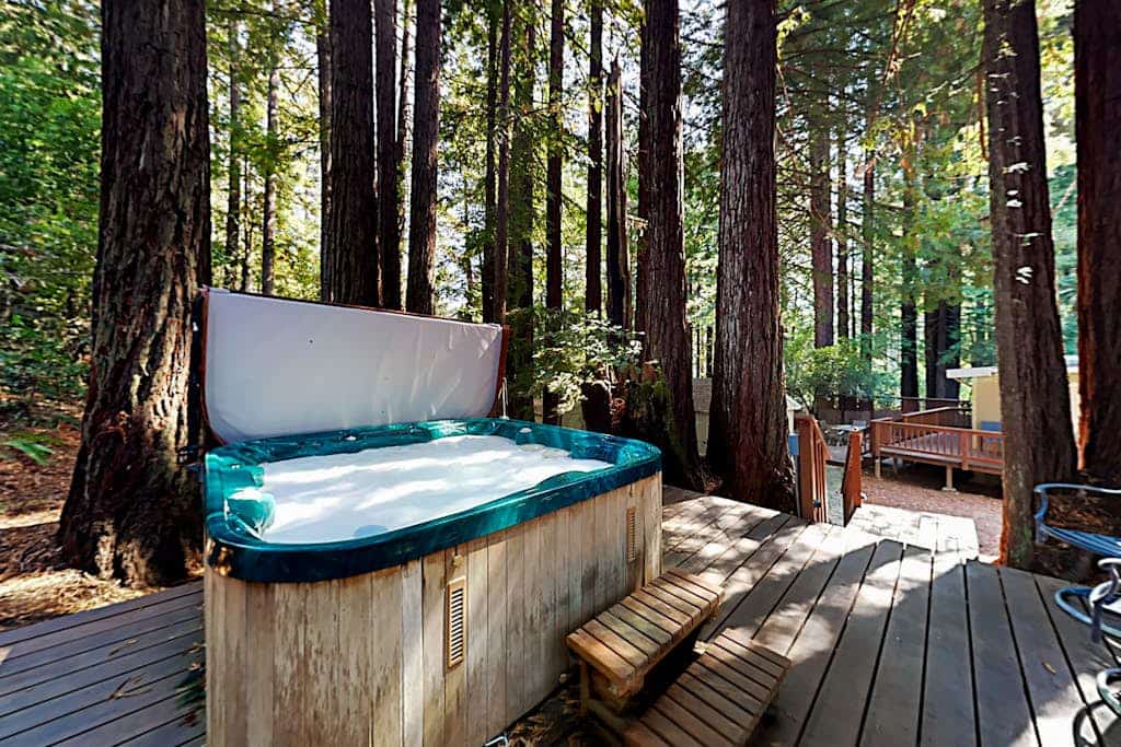 Soak in the deck hot tub as redwoods tower around this Cazadero retreat. Inside, knotty pine cabinets meet dark granite at the U-shaped kitchen, and a black wood stove warms the open living room. Walk forest paths 0.7 miles to Point of ridge, or 1.5 miles to Cape Fear Café. Dogs welcome.
