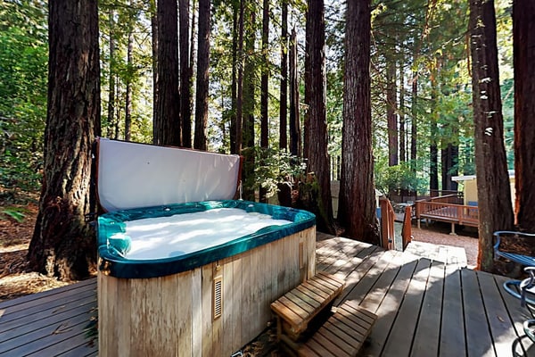 Soak in the deck hot tub as redwoods tower around this Cazadero retreat. Inside, knotty pine cabinets meet dark granite at the U-shaped kitchen, and a black wood stove warms the open living room. Walk forest paths 0.7 miles to Point of ridge, or 1.5 miles to Cape Fear Café. Dogs welcome.