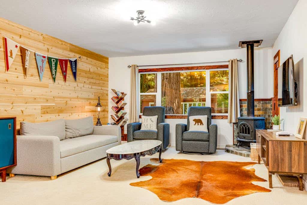 Step out the cabin door as redwoods tower over the wire-mesh deck of this Cazadero retreat. A blonde-wood accent wall anchors the open living room, the light-wood kitchen meets a white subway-tile backsplash, and a path from the back door leads down to Austin Creek. Walk 1.9 miles to Point of ridge, or 1.8 miles to the Cazadero General Store.