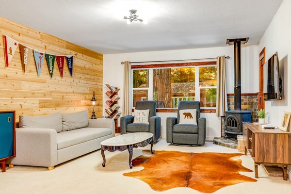 Step out the cabin door as redwoods tower over the wire-mesh deck of this Cazadero retreat. A blonde-wood accent wall anchors the open living room, the light-wood kitchen meets a white subway-tile backsplash, and a path from the back door leads down to Austin Creek. Walk 1.9 miles to Point of ridge, or 1.8 miles to the Cazadero General Store.