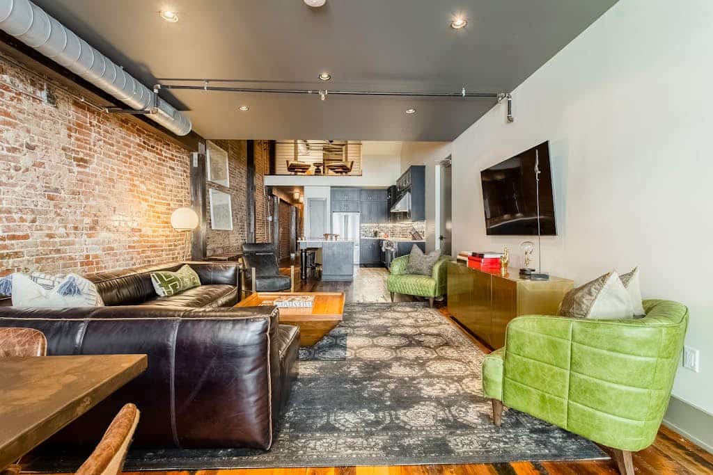 Stay in a stylish 4-bedroom, 4-bath downtown Nashville loft with exposed brick, a full kitchen, wet bar, and room for 14. Sleeping spaces include two king bedrooms, one queen bedroom, and a bunk room with four queen beds. Restaurants and entertainment are within walking distance. Please note: the building has no elevator, and parking is paid off-site.