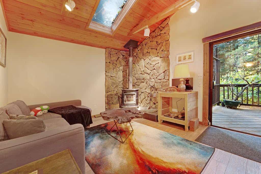 A stone hearth with a wood burning stove anchors this peaceful forest hideaway, where towering redwoods shade every window. Gather around the stone fireplace or grill dinner on the deck while kids play in the enclosed yard — this 2-bedroom cottage sleeps 4 comfortably. Just a 5-minute walk to a community beach with river access and a mile from Lightwave Coffee. Your days here move at redwood pace — slow, grounded, and deeply restorative among these ancient giants.