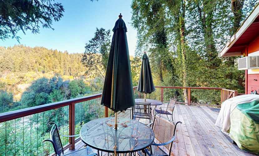Sunlight filters through towering redwoods as you sip morning coffee on the wraparound deck overlooking the Russian River. This dog-friendly retreat sleeps 8 with three bedrooms and an impressive outdoor kitchen complete with dual grills and smoker. Your private neighborhood beach sits right in the backyard — launch kayaks or simply wade into the gentle current. Just 5 minutes from downtown Guerneville's restaurants and 2 miles to Armstrong Redwoods. The river calls, and your cabin awaits.