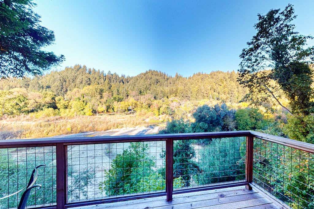 Sunlight filters through towering redwoods as you sip morning coffee on the wraparound deck overlooking the Russian River. This dog-friendly retreat sleeps 8 with three bedrooms and an impressive outdoor kitchen complete with dual grills and smoker. Your private neighborhood beach sits right in the backyard — launch kayaks or simply wade into the gentle current. Just 5 minutes from downtown Guerneville's restaurants and 2 miles to Armstrong Redwoods. The river calls, and your cabin awaits.