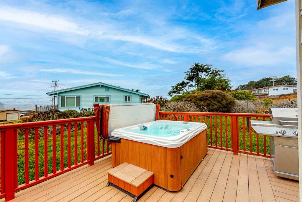 Soak in the private hot tub as Pacific fog burns off the bluff, then walk five minutes to Schoolhouse Beach or Carmet Beach to comb for sea glass and driftwood. This nautical-themed Carmet cottage sleeps 5 across two queen bedrooms and a sofa bed, with a wrap-around deck, gas grill, and ocean views from the living room. Dogs welcome.