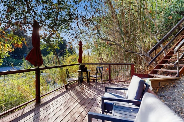 Step onto your private dock and watch the Russian River slide past while oak-covered hillsides frame the view. Two stacked units — each with its own entrance, patio, and bathroom — make this riverfront stay work for two couples or a family of four. A bocce court, big yard, and canoe wait outside, and downtown Healdsburg's wineries and fine dining are 2.4 miles away.