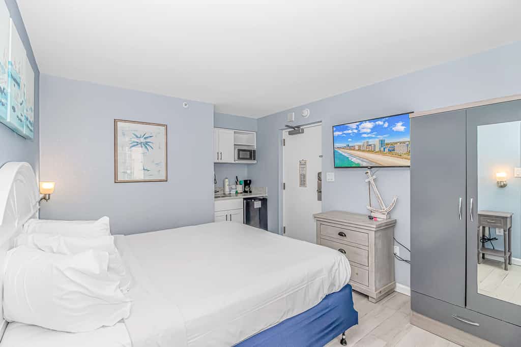 Check out this direct ocean view vacation rental at Boardwalk Resort in Myrtle Beach, SC. This ocean view vacation rental is fully furnished with everything you need for your next vacation. This apartment features 1 king bed and will comfortably accommodate 2 guests. This rental is a studio condo which means that it's basically the size of a hotel room. The living space consists of 1 king bed, multiple dressers for storage, wardrobe closet, Smart TV with basic cable, mini kitchenette, AC and Heat unit, a private balcony, and a private full-size bathroom. The bathroom features a tub/shower, granite countertop, new faucet, new vanity, and toilet. Our guests love having access to their own private balcony in the bedroom.