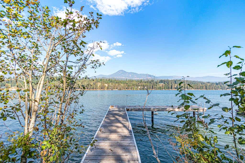 Riverfront ranch with large deck, fire pit, dock, W/D, & mountain view