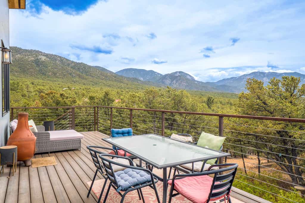 Welcome to Piñon Ridge Retreat, a striking modern home tucked into the piñon forest above Valdez, where walls of glass frame the Sangre de Cristo peaks from nearly every room. Wake to forest light in ground-floor bedrooms, gather in the window-wrapped upper living space, and step onto the deck to grill at sunset. Soak in the private hot tub under the stars, trade volleys at the ping pong table, and unwind by the fire. Modern, secluded, and quiet, with Taos and the Ski Valley a short drive away.