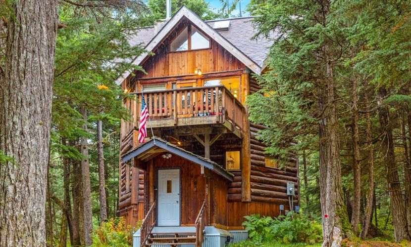 Ullr is the Norse god of snow, and his treehouse is exactly what it sounds like—a highly unique, 1,400 sq. ft. hexagonal cabin that climbs straight up into the spruce canopy across four distinct, 350 sq. ft. levels. Bordering Chugach State Park land, the back path connects you to Beaver Pond Trail for foot treks into town. The layout rises into the trees to offer intimate, custom spaces: a basement media room with a PS4, a second-floor leather lounge and compact kitchen, and a lofted primary bedroom under sloped timbers. Outside, a massive hot tub waits beneath the old-growth tree canopy. *Just be ready to summon your inner mountain goat for the four flights of stairs.* Standard Specs: Full compact kitchen, outdoor hot tub, gas fireplace, private washer/dryer, PS4 console, flat-screen TVs, high-speed WiFi, and keypad entry. Driveway parking for up to four vehicles. On the Glacier Valley Transit route. Sleeps 6.