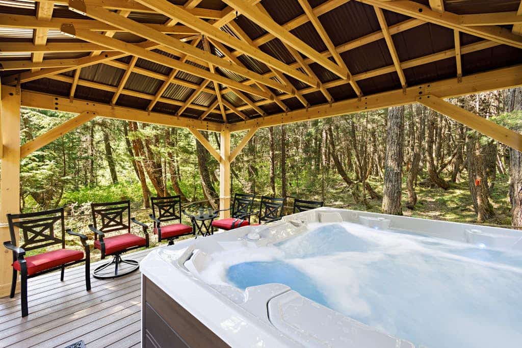 Ullr is the Norse god of snow, and his treehouse is exactly what it sounds like—a highly unique, 1,400 sq. ft. hexagonal cabin that climbs straight up into the spruce canopy across four distinct, 350 sq. ft. levels. Bordering Chugach State Park land, the back path connects you to Beaver Pond Trail for foot treks into town. The layout rises into the trees to offer intimate, custom spaces: a basement media room with a PS4, a second-floor leather lounge and compact kitchen, and a lofted primary bedroom under sloped timbers. Outside, a massive hot tub waits beneath the old-growth tree canopy. *Just be ready to summon your inner mountain goat for the four flights of stairs.* Standard Specs: Full compact kitchen, outdoor hot tub, gas fireplace, private washer/dryer, PS4 console, flat-screen TVs, high-speed WiFi, and keypad entry. Driveway parking for up to four vehicles. On the Glacier Valley Transit route. Sleeps 6.