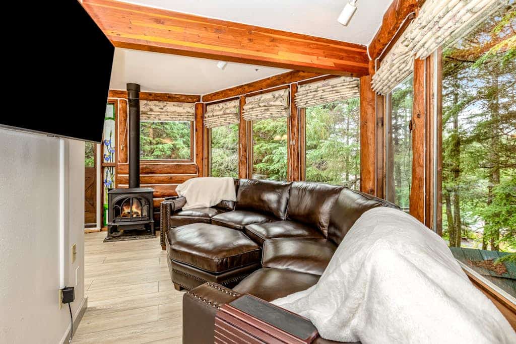 Ullr is the Norse god of snow, and his treehouse is exactly what it sounds like—a highly unique, 1,400 sq. ft. hexagonal cabin that climbs straight up into the spruce canopy across four distinct, 350 sq. ft. levels. Bordering Chugach State Park land, the back path connects you to Beaver Pond Trail for foot treks into town. The layout rises into the trees to offer intimate, custom spaces: a basement media room with a PS4, a second-floor leather lounge and compact kitchen, and a lofted primary bedroom under sloped timbers. Outside, a massive hot tub waits beneath the old-growth tree canopy. *Just be ready to summon your inner mountain goat for the four flights of stairs.* Standard Specs: Full compact kitchen, outdoor hot tub, gas fireplace, private washer/dryer, PS4 console, flat-screen TVs, high-speed WiFi, and keypad entry. Driveway parking for up to four vehicles. On the Glacier Valley Transit route. Sleeps 6.