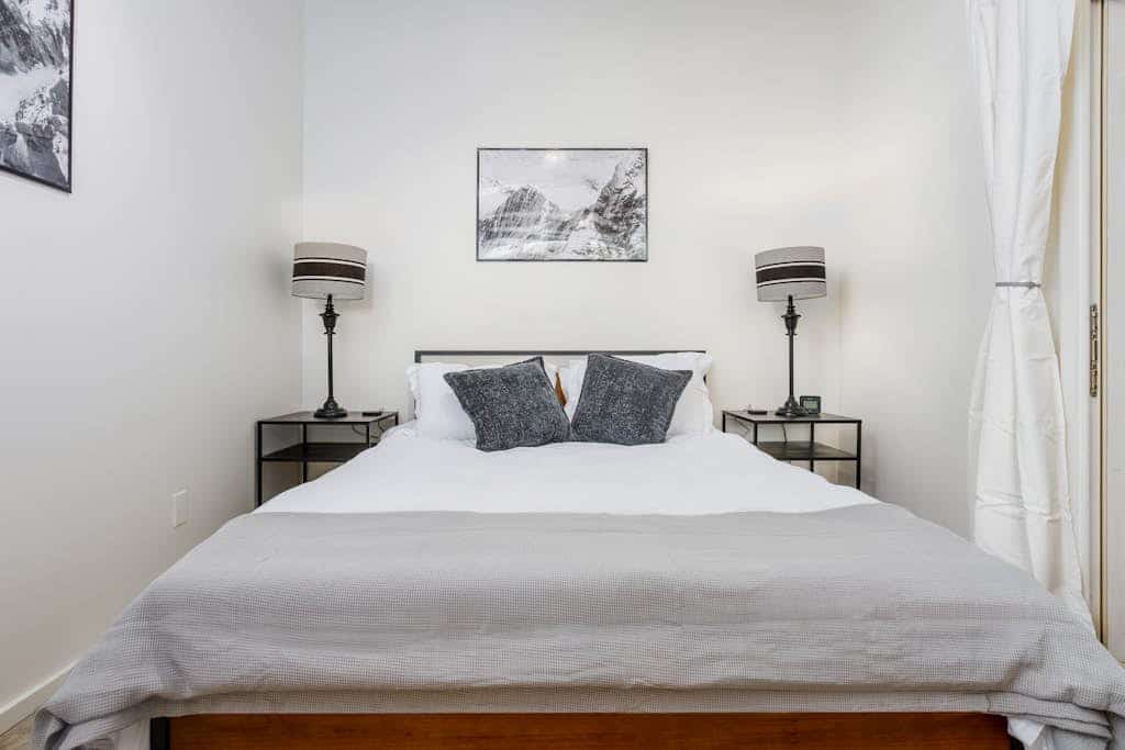 Industrial-chic finishes meet a private park-like setting. Tucked directly into downtown Anchorage's historic Bootlegger Cove neighborhood, this unique triplex unit features a bright interior with large windows that pull in natural light and capture clean views of the Cook Inlet waters. The sleek interior boasts a custom gas fireplace, modern design elements, and a high-end kitchenette packed with gourmet gadgets including an air fryer and a Ninja blender system. The master bedroom opens directly onto a beautifully furnished garden patio, complete with a private outdoor hot tub. Walk to the Tony Knowles Coastal Trail, downtown eateries, and museums in seconds. Standard Specs: Premium kitchenette (air fryer, Ninja system, toaster, fridge), built-in gas fireplace, private outdoor hot tub, shared garden patio, flat-screen TV, high-speed WiFi, and keypad entry. Driveway parking for one vehicle. Built for small families or executive stays. Sleeps 5.