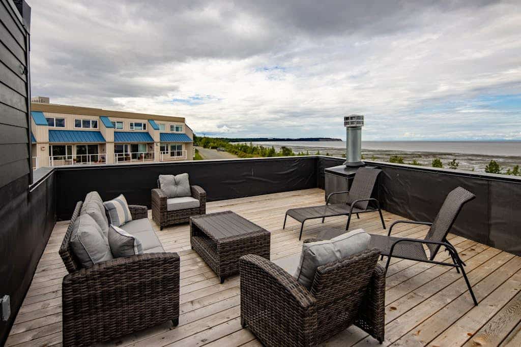 A luxury two-story loft villa in downtown Anchorage built with elegant professional design and high-end finishes engineered for sophisticated comfort. Located in coveted Bootlegger’s Cove, the home captures clean views of Cook Inlet and the Alaska Range from its massive windows, covered balcony, and private rooftop deck. The open floor plan features a built-in wet bar for happy hours, a gourmet kitchen packed with chef-grade appliances, a dual-sided gas fireplace, and a private hot tub standing by on the deck for soothing soaks. Walk to the historic Coastal Trail system or use the provided bicycles to explore 150+ miles of interconnecting trails surrounding the estate. Standard Specs: Chef's kitchen with high-end appliances, private wet bar, rooftop deck, private hot tub, deluxe gas grill, dual-sided fireplace, private bicycles, in-unit laundry, flat-screen Smart TVs, high-speed WiFi, and keypad entry. Parking for two vehicles. Sleeps 10.