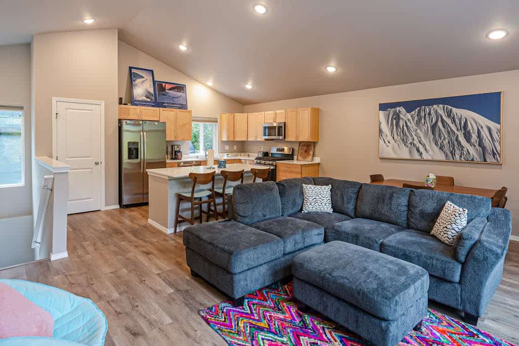 Both independent sides of our premium Girdwood duplex combined into a single, high-capacity mountain home sleeping up to ten guests under one roof. It is the perfect operational call when your family group is larger than a single unit can handle, but you still want everyone sharing the same basecamp. The open-concept layout features modern radiant floor heating throughout, two fully equipped kitchens with stainless steel appliances, two distinct living rooms with oversized sofas and Smart TVs, and a child's playroom packed with toys and books. Step outside to access dual viewing decks and a shared grilling area framed by breathtaking views of the surrounding Girdwood wilderness. Walk to the Virgin Creek Trailhead. Standard Specs: High-capacity duplex layout with two full kitchens, radiant floor heat, shared gas grilling decks, mountain views, private washer/dryers, Pack-N-Plays, child's toys, flat-screen Smart TVs, high-speed WiFi, and keypad entry. Driveway parking for up to four vehicles. No A/C. Sleeps 10.