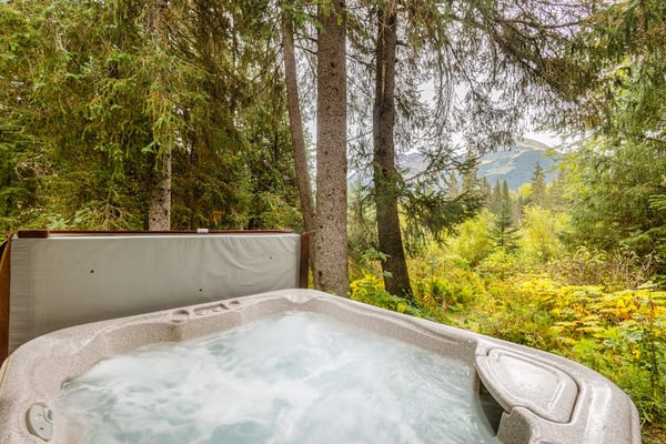 There is a moment when the highway falls away, the spruce closes in, and the only sound is the water out back. That is Iris Pond. Handcrafted with custom wood-carved interiors, this private Girdwood cabin pairs rugged Alaska character with polished hospitality, sitting just a few minutes from the chairlifts at Alyeska. The open layout features large windows framing the forest, a fully equipped chef's kitchen, and a seamless transition to the back deck where a private hot tub waits beneath the trees. It is a quiet, clean basecamp built for slow mornings with local coffee and long evenings after hiking Chugach National Forest trailheads or chasing deep powder. Standard Specs: Fully equipped kitchen, private washer/dryer, flat-screen TV, high-speed WiFi, and keypad entry. Safe parking for up to four vehicles. Sleeps 7.