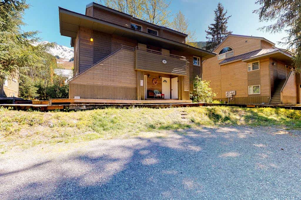 Girdwood lives at a slower rhythm, and this remodeled, split-level condo fits right into it. Tucked into a quiet stand of forest in central Girdwood, the home features clean views out every single window and the kind of quiet that makes you forget how close you are to the village core. The two-story layout easily handles a full crew without feeling crowded, offering a bright living zone centered around a stone gas fireplace, an updated kitchen, and a master bathroom with a deep jetted soaking tub to revive trail-weary legs. Walk out your door to find the local bike path, The Bake Shop, and the local mercantile just minutes away. Standard Specs: Full kitchen with dishwasher, private full-size washer/dryer, flat-screen cable TV, high-speed WiFi, and keypad entry. Dedicated parking for two vehicles. Sleeps 7.