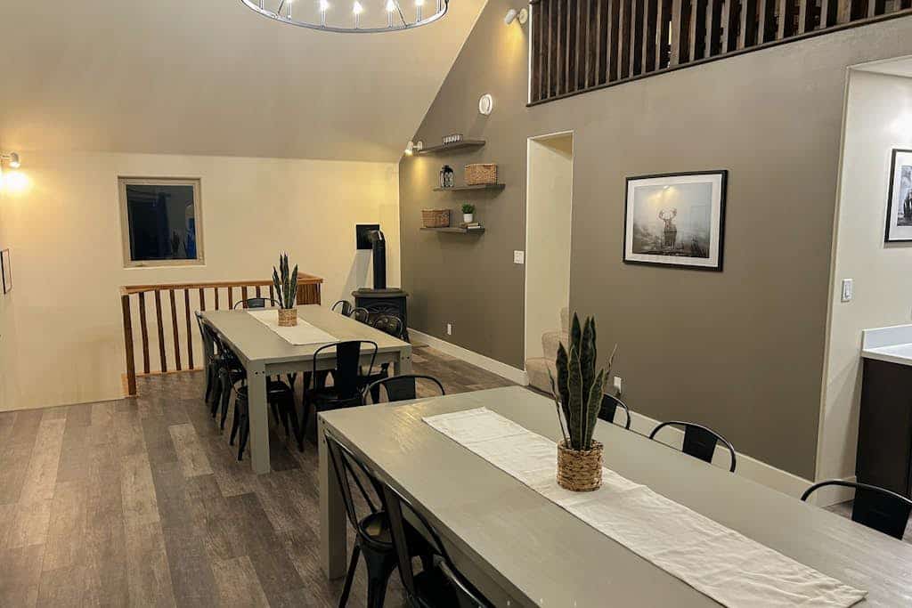 When the corporate retreat, family reunion, or wedding party requires a footprint larger than a standard mountain house can handle—The Monarch handles it with ease. This newly remodeled 9-bedroom plus loft Girdwood estate comfortably sleeps up to twenty-one guests across two independent, masterfully crafted duplex levels (Unit A and Unit B). The private lot features a massive viewing deck for morning coffee, a pro gas grill, and a custom stone fire pit for long evenings under the stars. The interior provides multiple open living zones, dual fully equipped kitchens, a stone fireplace, and bedrooms with data-verified mountain views. The iconic Bird-to-Gird biking path sits steps from the door, the Girdwood Train Depot is a 5-minute walk, and Alyeska Resort is minutes ahead. Standard Specs: Sprawling duplex compound with dual full kitchens, stone fireplace, stone fire pit, gas grill, flat-screen streaming TVs, high-speed WiFi, and keypad entry. Massive private lot with parking space for up to ten vehicles. Walk to Girdwood Station. Sleeps 21.