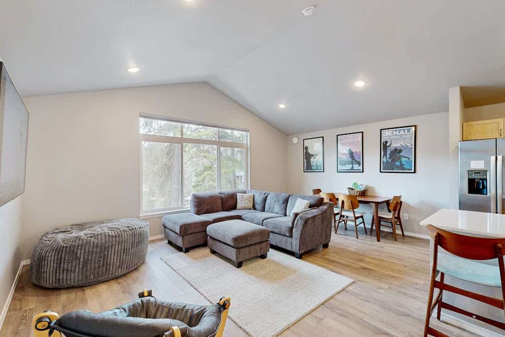 Modern radiant floor heating is the subtle operational detail that turns a winter ski trip into a true luxury upgrade—and Girdwood Vibes Unit B features it throughout the entire open-concept floor plan. Located within easy walking distance of Alyeska Resort and the Virgin Creek Trailhead, this suite handles family logistics effortlessly. The interior features an oversized living room sofa, a large custom bean bag, a massive Smart TV, and a full kitchen with stainless steel appliances. The dedicated kid's room comes fully stocked with toys, books, and games to handle the entertainment heavy lifting, while the back deck opens out to a shared grilling area framed by clean mountain peaks. Standard Specs: Full kitchen with stainless steel appliances, radiant floor heating, shared deck with gas grill, private washer/dryer, flat-screen Smart TV, child's toys, games, books, Pack-N-Play, high-speed WiFi, and keypad entry. Parking for two vehicles. No A/C. Sleeps 6.